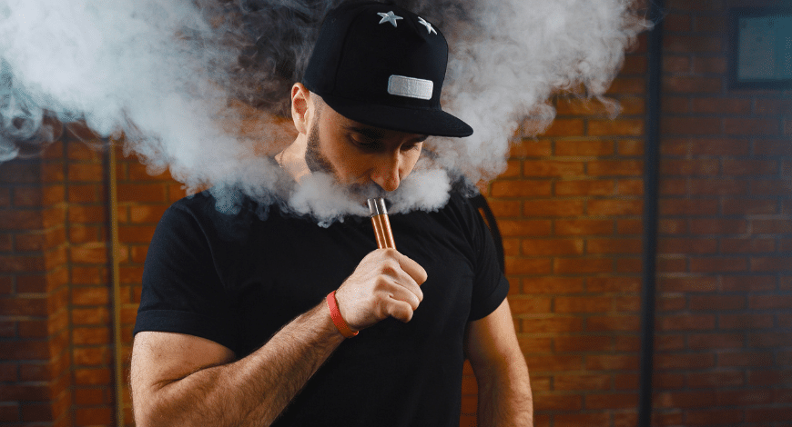 Man exhaling vapor while using a dab pen, representing the search for high-quality dab pens for optimal cannabis experience