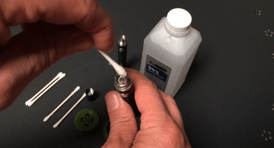 Person using and cleaning a wax pen, showing cannabis vaping care tips