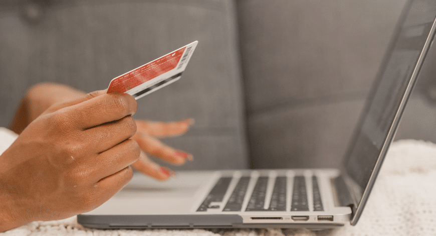 Person holding a credit card while shopping on a laptop, symbolizing online purchase of quality cannabis like the Peanut Butter Breath strain