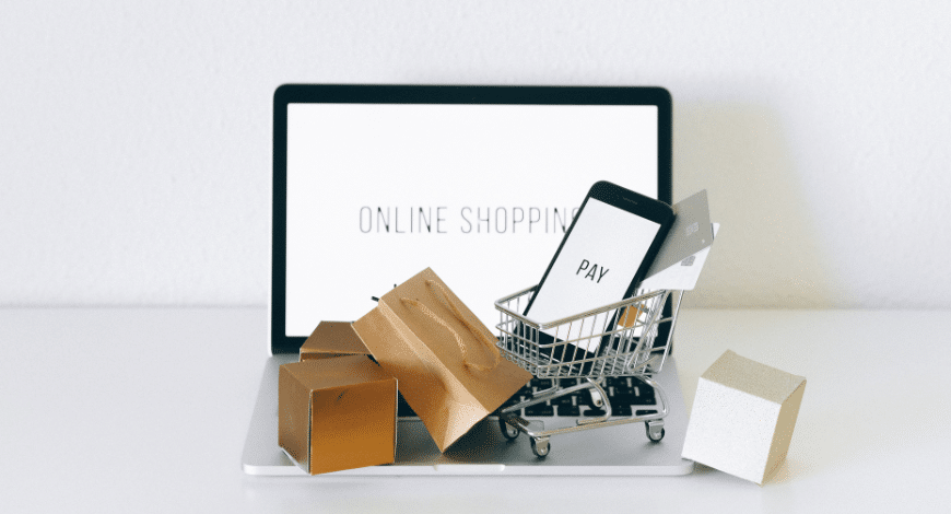 Mini shopping cart with phone and credit card on laptop displaying 'Online Shopping', representing where to buy Delta 8 online