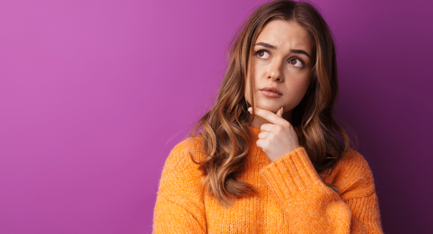 Thoughtful woman in orange sweater looking up, symbolizing curiosity about why to use a disposable weed vape